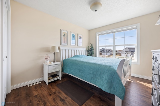 bedroom featuring visible vents, baseboards, a textured ceiling, and dark wood-style flooring