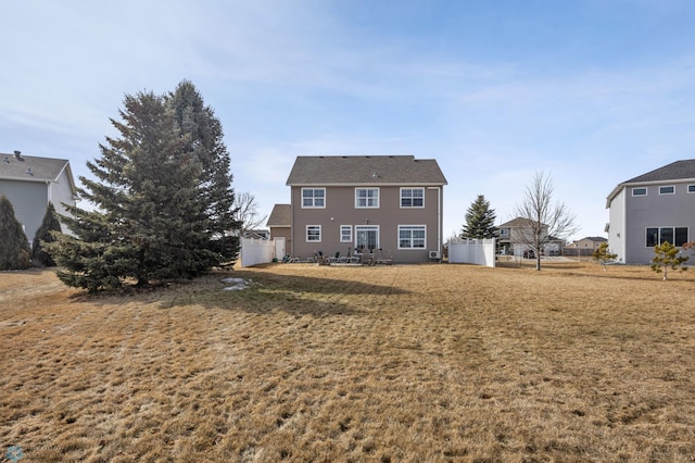 rear view of house featuring a lawn and fence