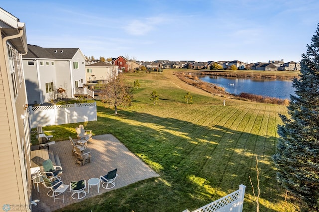 view of yard with fence, a patio area, a residential view, and a water view