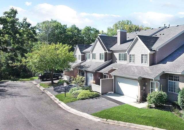 view of front of property featuring a garage, a chimney, aphalt driveway, roof with shingles, and brick siding