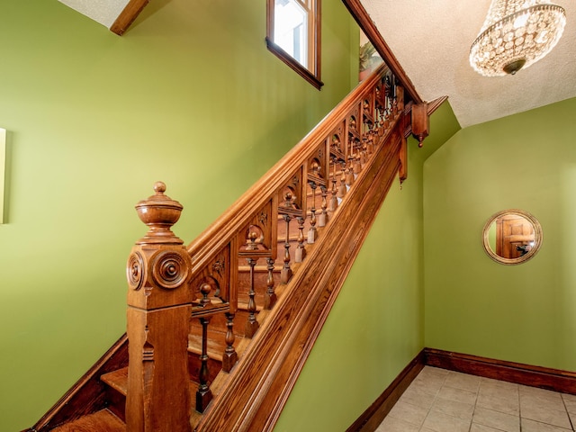 stairs with a textured ceiling, tile patterned flooring, and baseboards