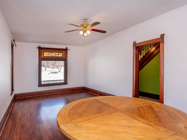 spare room with dark wood finished floors, baseboards, and ceiling fan