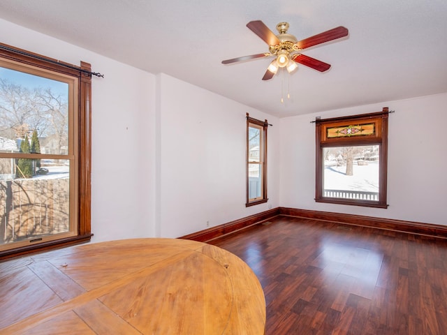 interior space featuring ceiling fan, baseboards, and dark wood finished floors