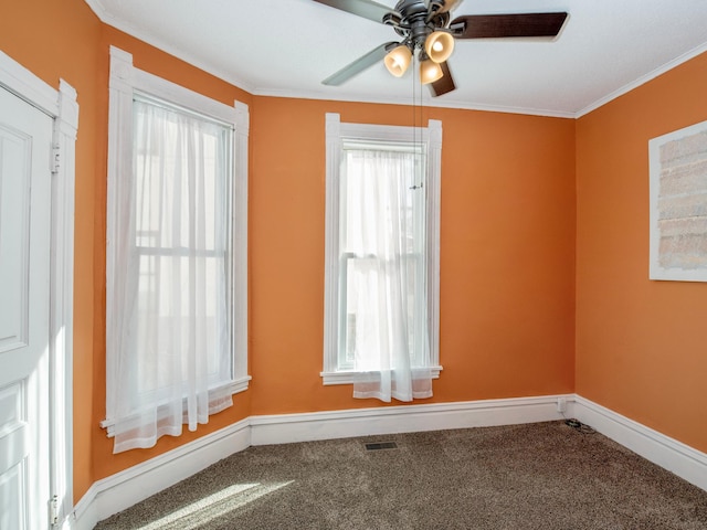 empty room featuring carpet floors, ornamental molding, plenty of natural light, and visible vents