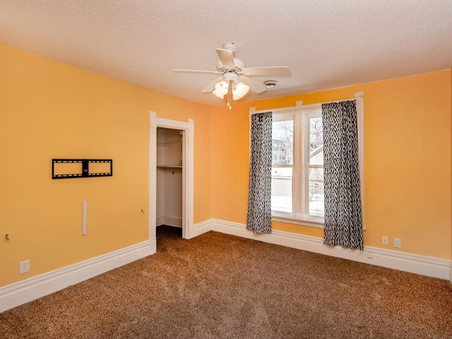 spare room featuring carpet floors, a ceiling fan, baseboards, and a textured ceiling