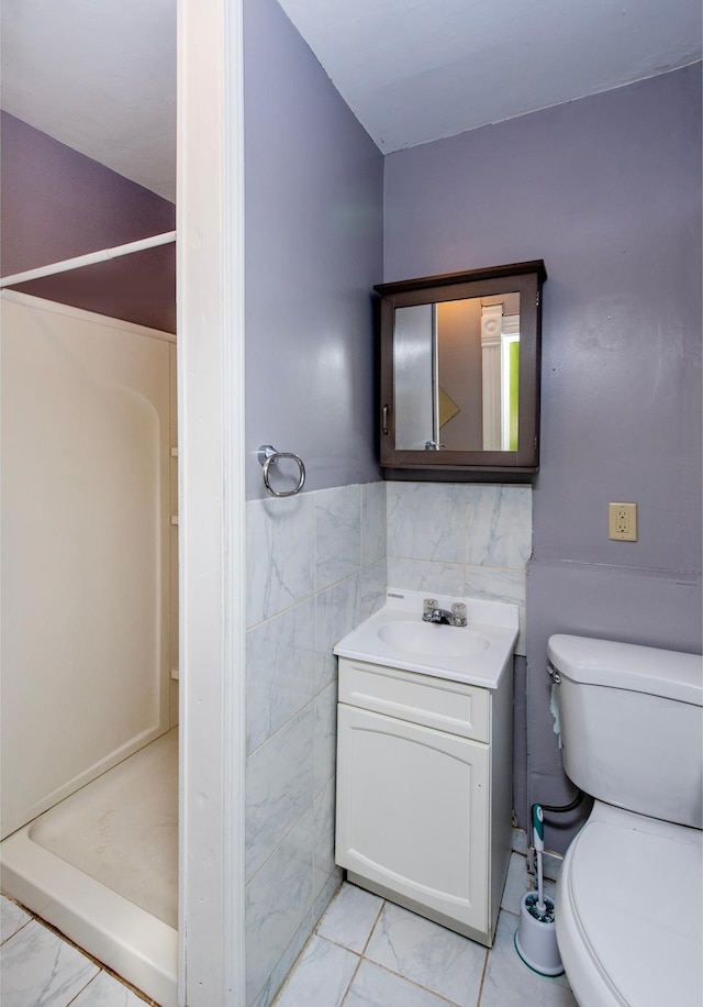 full bath featuring wainscoting, toilet, marble finish floor, vanity, and tile walls