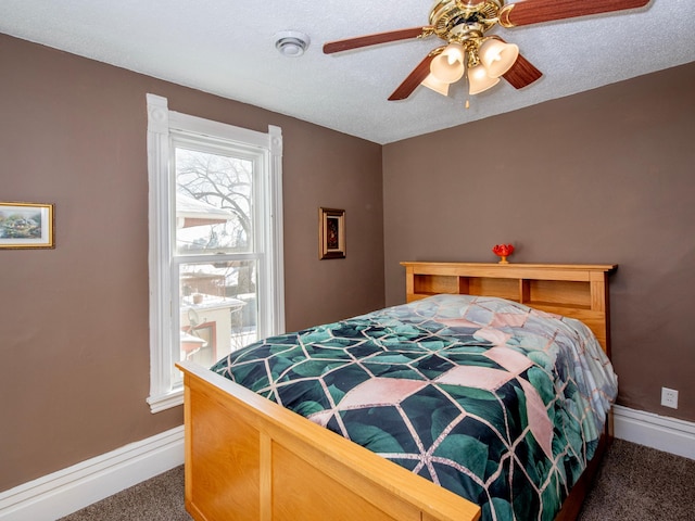 bedroom with dark carpet, a textured ceiling, baseboards, and ceiling fan