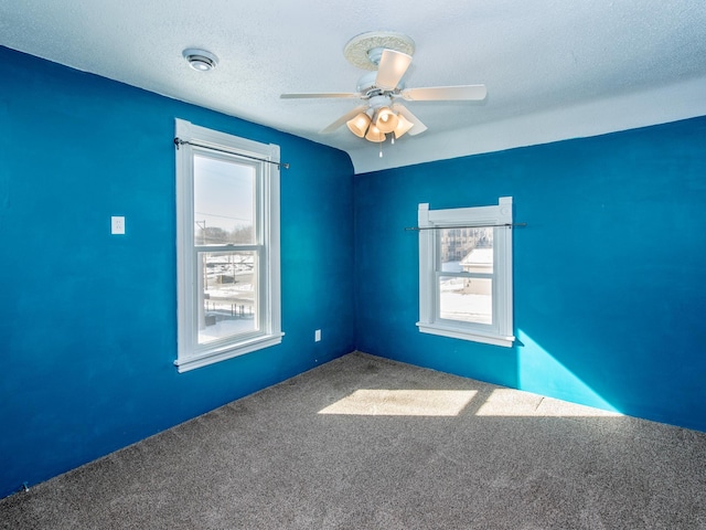 empty room with carpet flooring, ceiling fan, and a textured ceiling