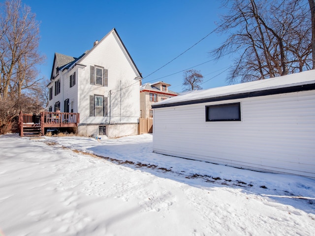 snow covered property with a chimney and a wooden deck