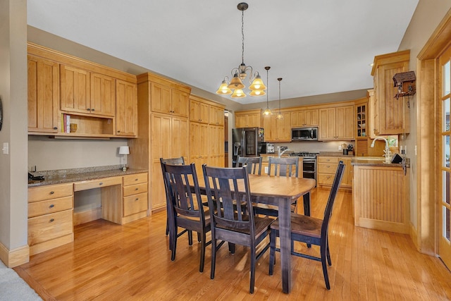 dining space featuring light wood-type flooring, an inviting chandelier, baseboards, and built in desk