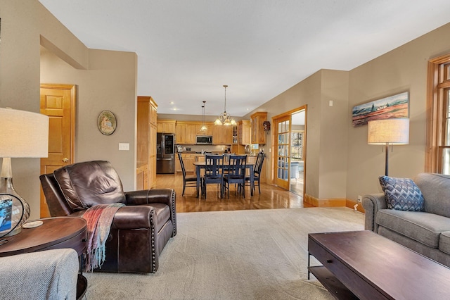 living room with an inviting chandelier, light colored carpet, and baseboards