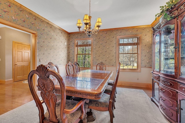 dining space featuring light wood finished floors, ornamental molding, wainscoting, and wallpapered walls