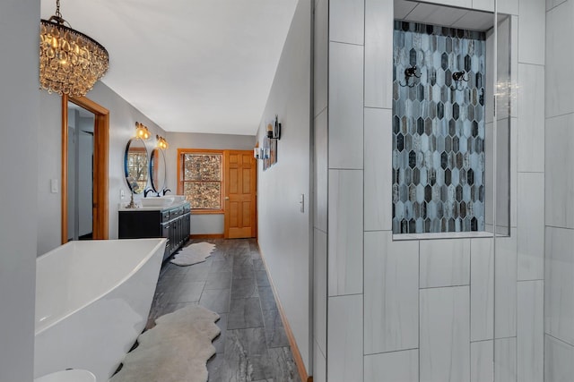 interior space featuring a stall shower, a freestanding tub, vanity, and baseboards