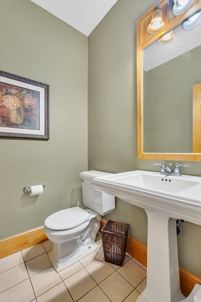 half bath featuring toilet, baseboards, and tile patterned floors