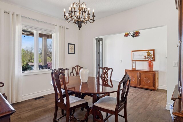 dining space featuring dark wood finished floors, a chandelier, and baseboards