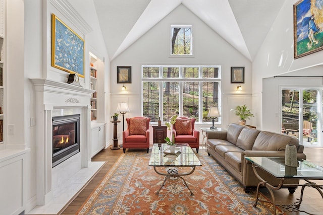 living room with built in shelves, a tile fireplace, wood finished floors, and high vaulted ceiling