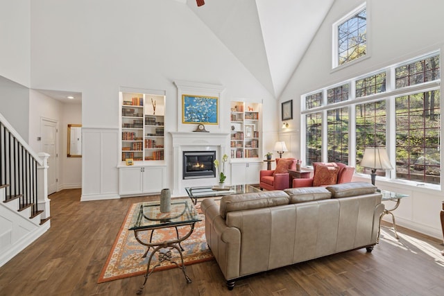 living area with high vaulted ceiling, plenty of natural light, dark wood-style floors, and a glass covered fireplace