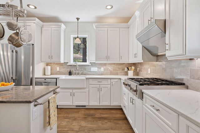 kitchen featuring stainless steel appliances, white cabinets, recessed lighting, under cabinet range hood, and hanging light fixtures