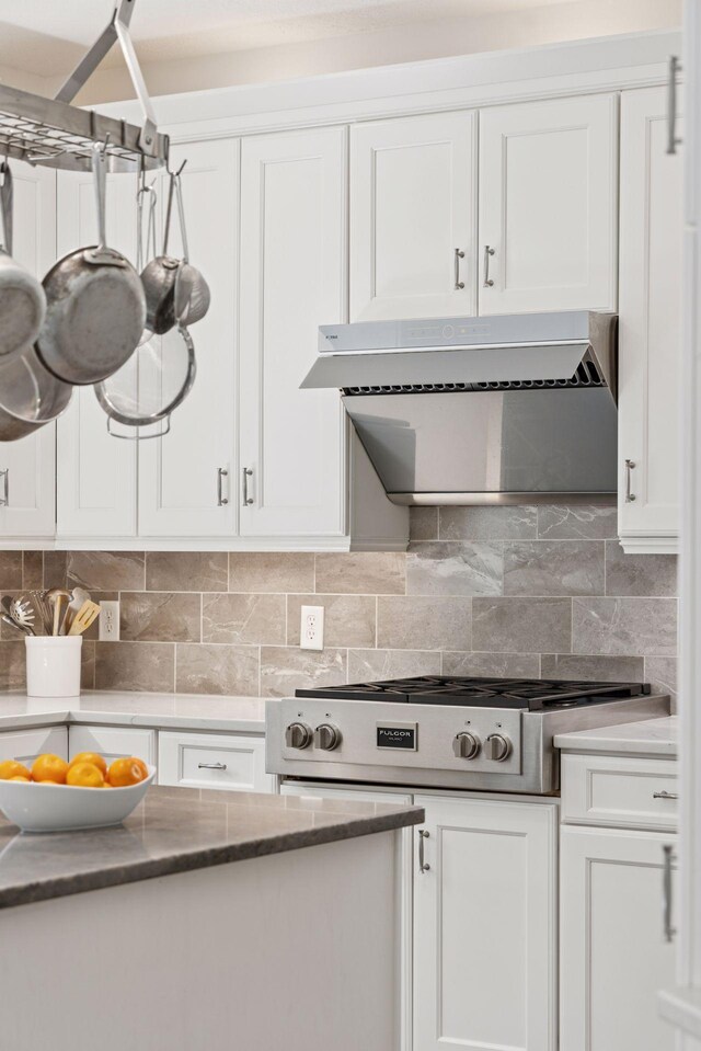 kitchen with white cabinets, decorative backsplash, dark stone countertops, and ventilation hood