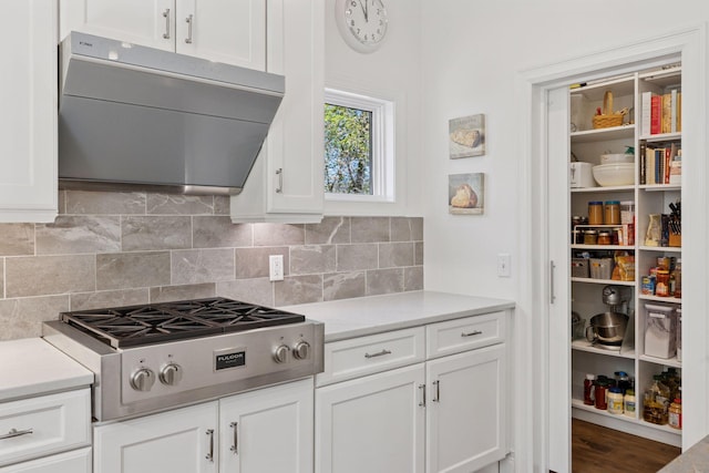 kitchen with range hood, stainless steel gas stovetop, white cabinetry, and light countertops
