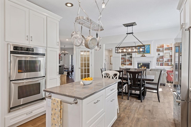 kitchen featuring stainless steel appliances, light stone counters, light wood finished floors, white cabinetry, and recessed lighting