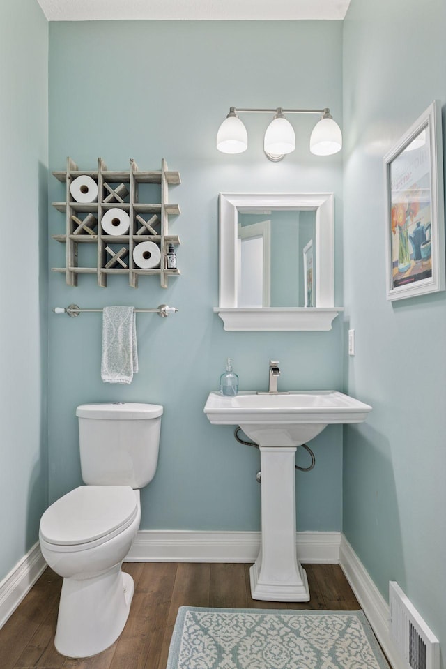 bathroom featuring baseboards, wood finished floors, and toilet