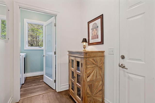 doorway to outside featuring washing machine and clothes dryer, wood finished floors, and baseboards