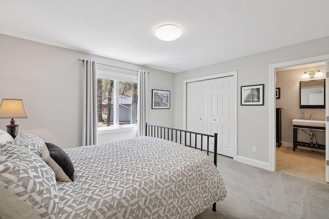 carpeted bedroom with a closet, baseboards, and connected bathroom