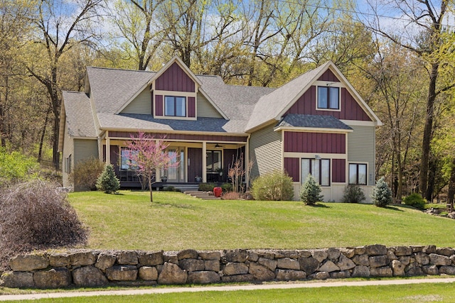 craftsman-style house featuring covered porch, a front yard, roof with shingles, ceiling fan, and board and batten siding
