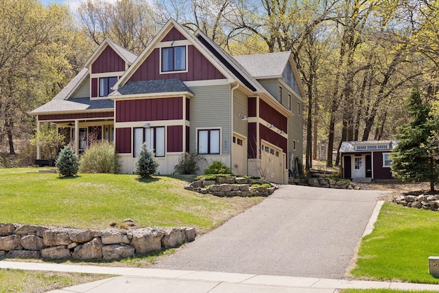 view of front of property featuring driveway, roof with shingles, a front yard, board and batten siding, and a garage