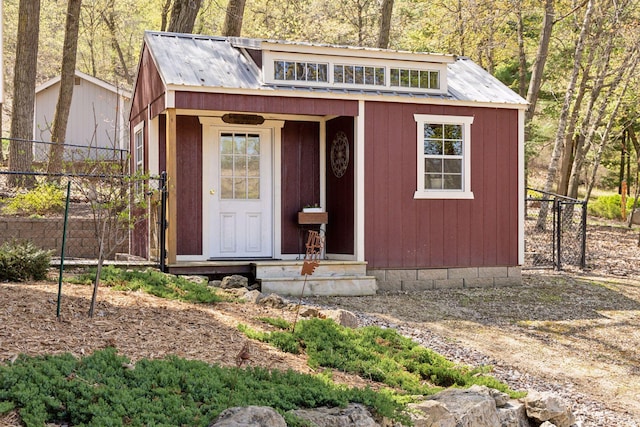 view of outdoor structure with fence, an outbuilding, and entry steps