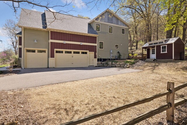1067 Pioneer Rd, Red Wing, MN 55066 - back of house with dirt driveway, roof with shingles, a garage, and an outdoor structure
