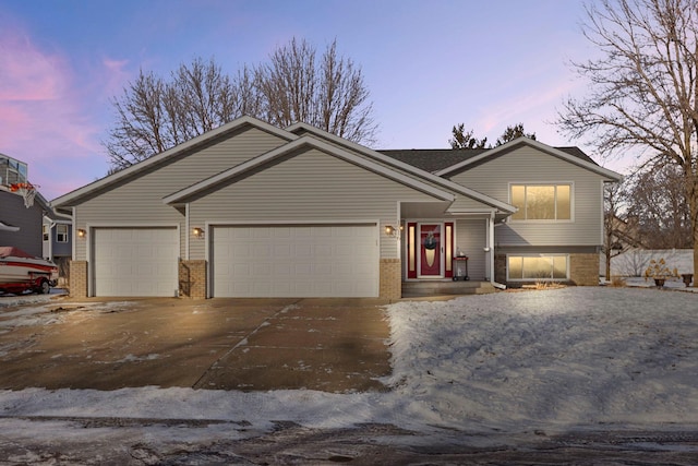 split level home with concrete driveway, brick siding, and an attached garage