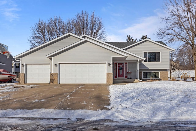 tri-level home featuring a garage, driveway, and brick siding