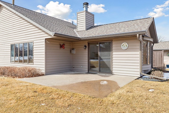 rear view of property with a yard, a patio, roof with shingles, and a chimney