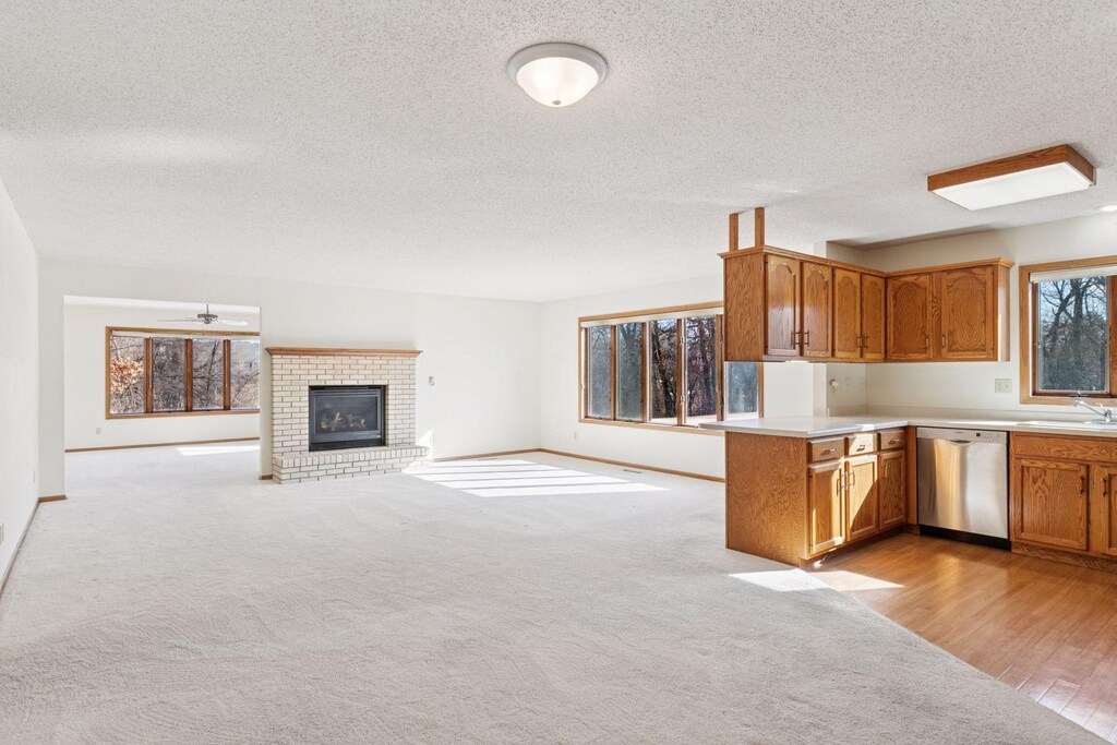 672 Hi Park Ave, Red Wing, MN 55066 - kitchen with a textured ceiling, dishwasher, light countertops, a brick fireplace, and open floor plan