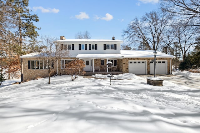 view of front of house with an attached garage, a chimney, a porch, and brick siding