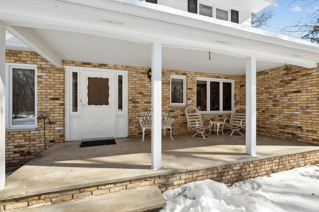 doorway to property with covered porch and brick siding