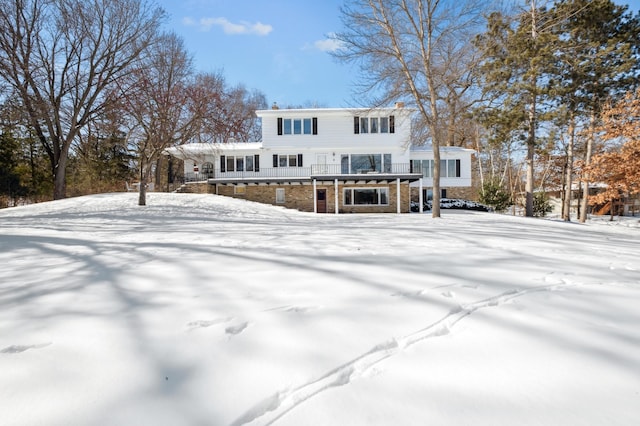 snow covered property featuring stone siding and a wooden deck