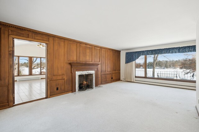 unfurnished living room featuring a fireplace, a baseboard radiator, baseboard heating, light carpet, and wood walls