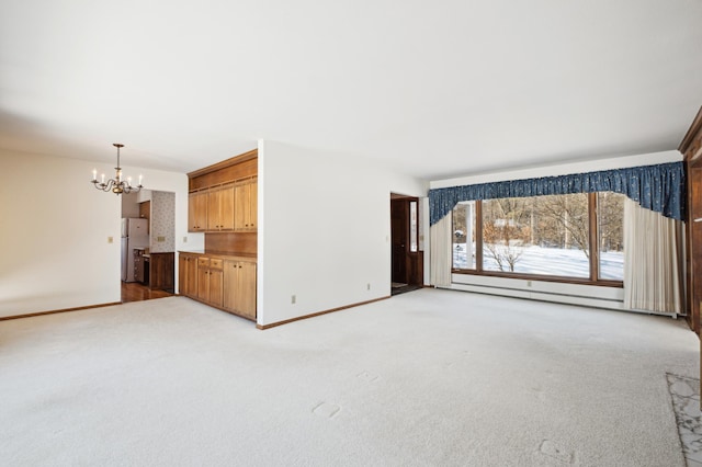 unfurnished living room with baseboards, a chandelier, and light colored carpet