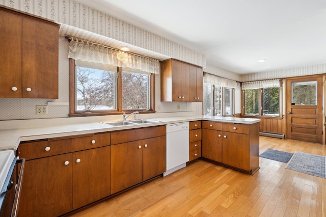 kitchen with a baseboard radiator, light countertops, a sink, dishwasher, and a peninsula