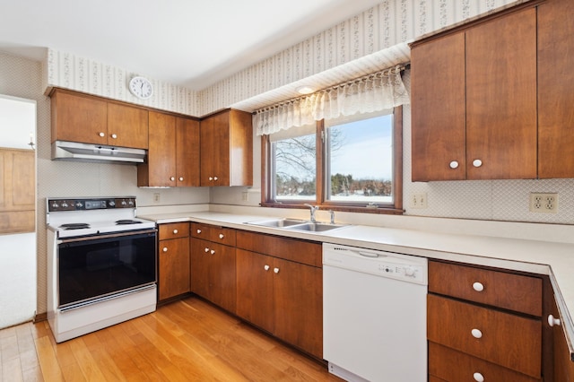 kitchen featuring under cabinet range hood, white appliances, a sink, light countertops, and wallpapered walls