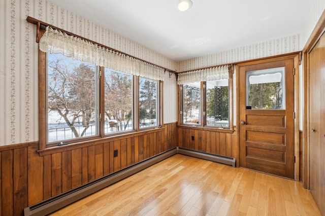 unfurnished sunroom featuring a baseboard heating unit and plenty of natural light