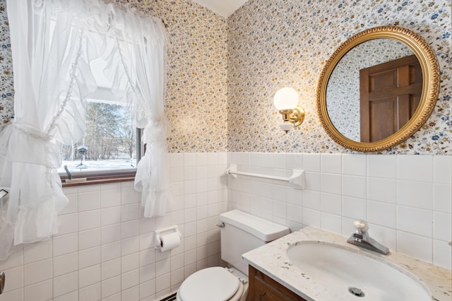 bathroom with wainscoting, tile walls, toilet, and wallpapered walls