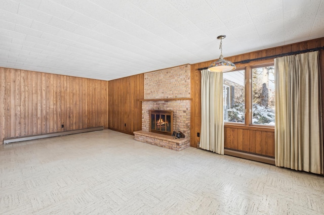 unfurnished living room with a baseboard radiator, a baseboard heating unit, wood walls, a brick fireplace, and light floors