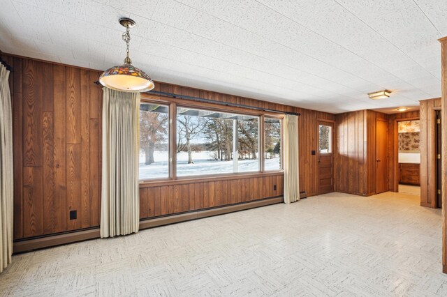 interior space featuring a baseboard heating unit, wooden walls, and light floors