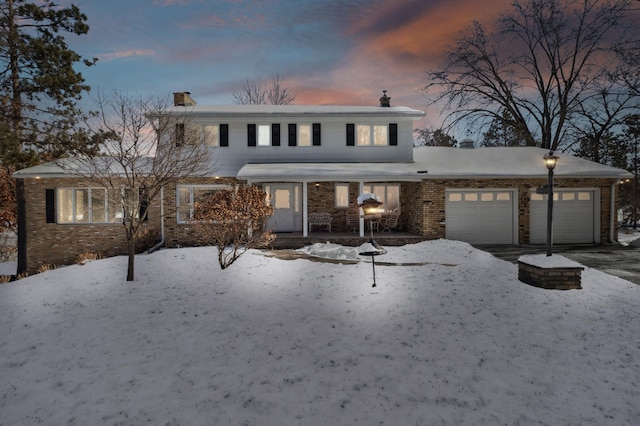 traditional home featuring brick siding, a chimney, and an attached garage