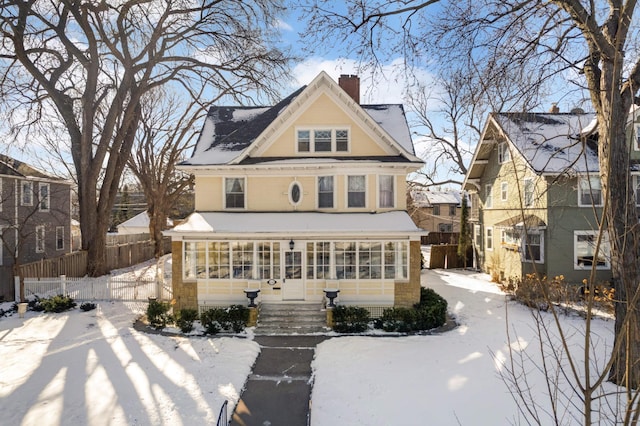 view of front facade with a chimney, fence, and a sunroom