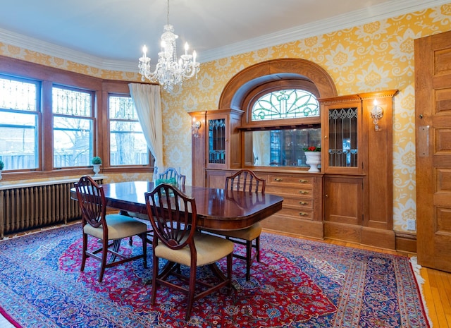 dining area featuring wood finished floors, plenty of natural light, radiator heating unit, and wallpapered walls